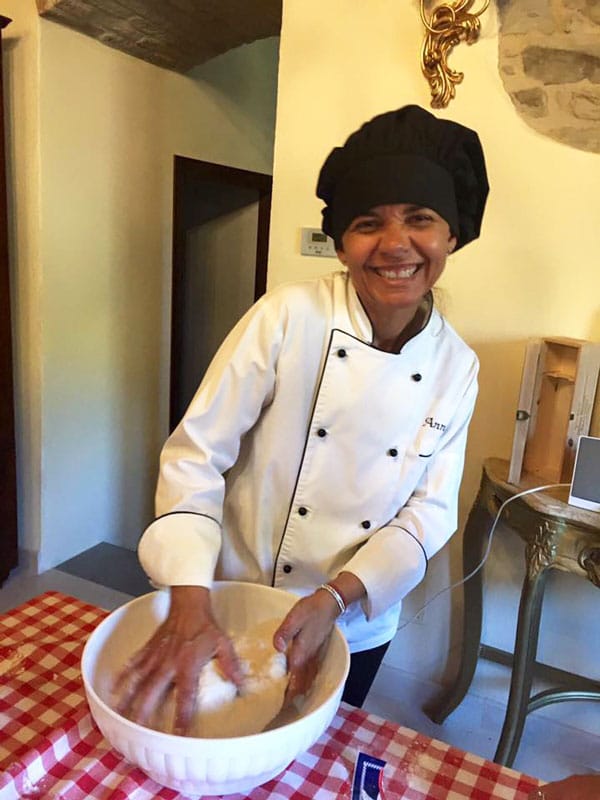 A female chef with a black chef's hat making pasta