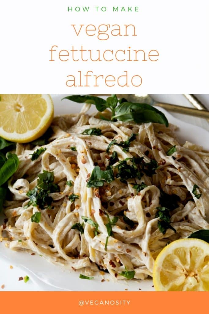 A Pinterest pin for vegan fettuccini Alfredo with a picture of a pile of the Alfredo on a white plate with lemon halves and chopped basil.