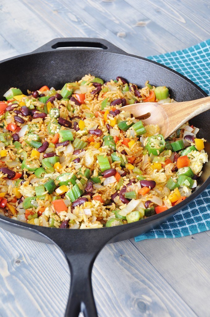 Fried rice with beans and vegetables in an iron skillet with a wooden spoon