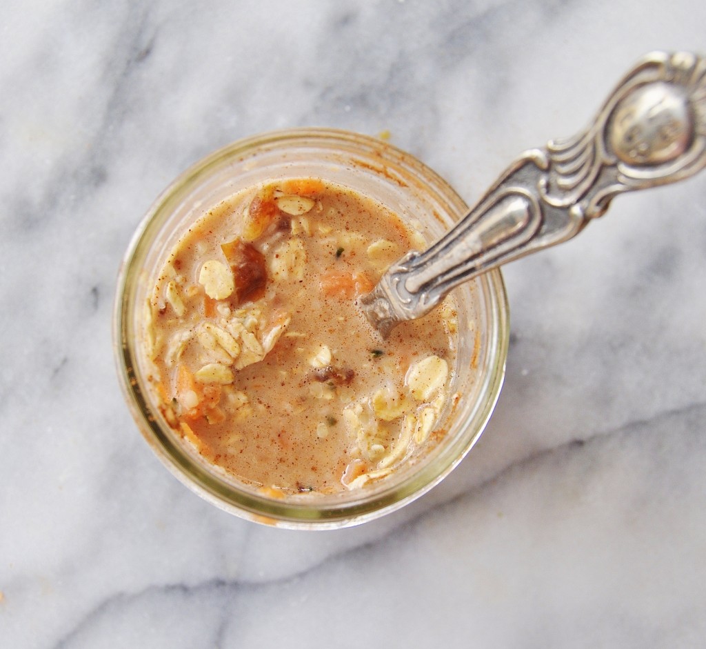 Vegan Carrot Cake Overnight Oats in a clear mason jar with a silver spoon stirring the oats