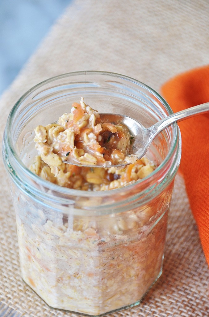 Vegan Carrot Cake Overnight Oats in a glass mason jar with a silver spoon in the jar and a burlap cloth and orange napkin under and next to the jar