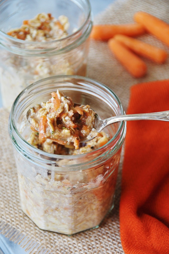 2 jars of Overnight Oats one with a silver spoon in it and an orange napkin and baby carrots next to the jars