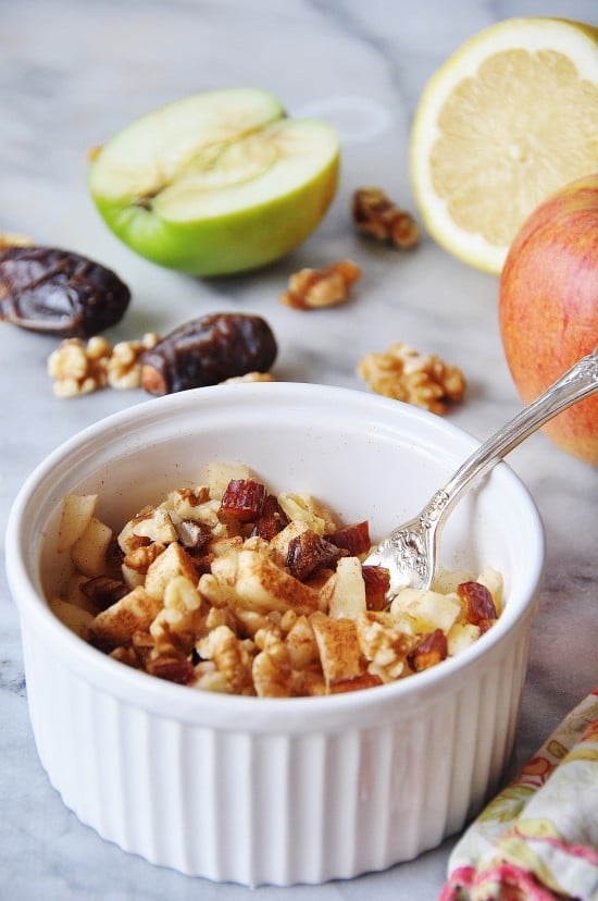 A white bowl filled with Raw Apple Pie and a silver fork is sticking out of it. 