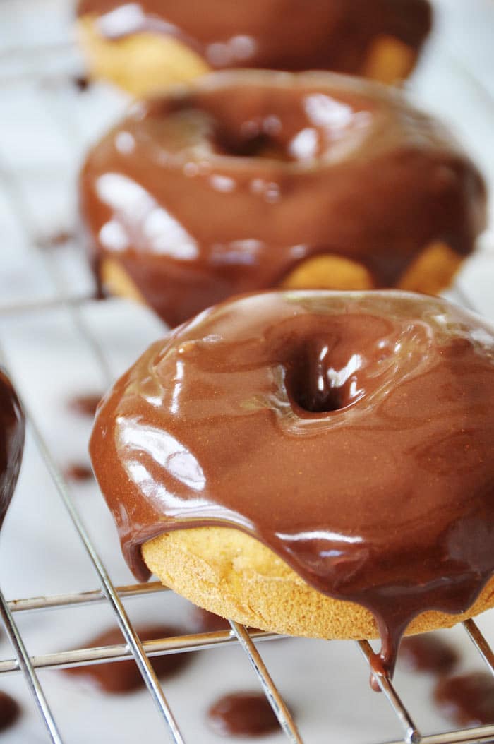 Baked-Vegan-Pumpkin-Spice-Doughnuts-with-Chocolate-Cinnamon-Icing on a wire rack