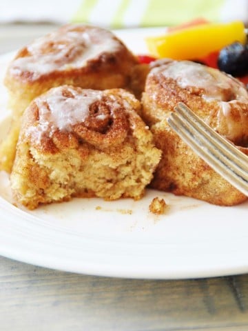 Homemade Vegan Cinnamon Rolls on a white plate with a silver fork