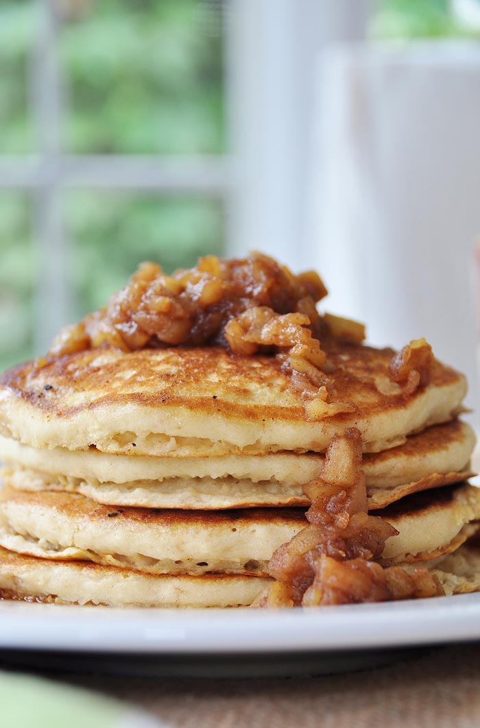 A stack of four Pancakes with Apple Spice Compote on top and dripping down the sides.