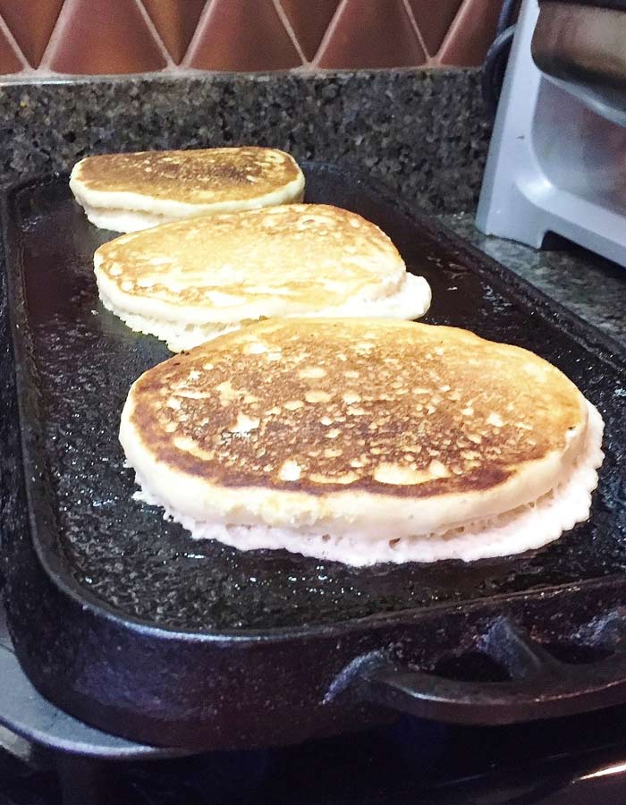 Golden brown fluffy vegan pancakes cooking on the griddle. 