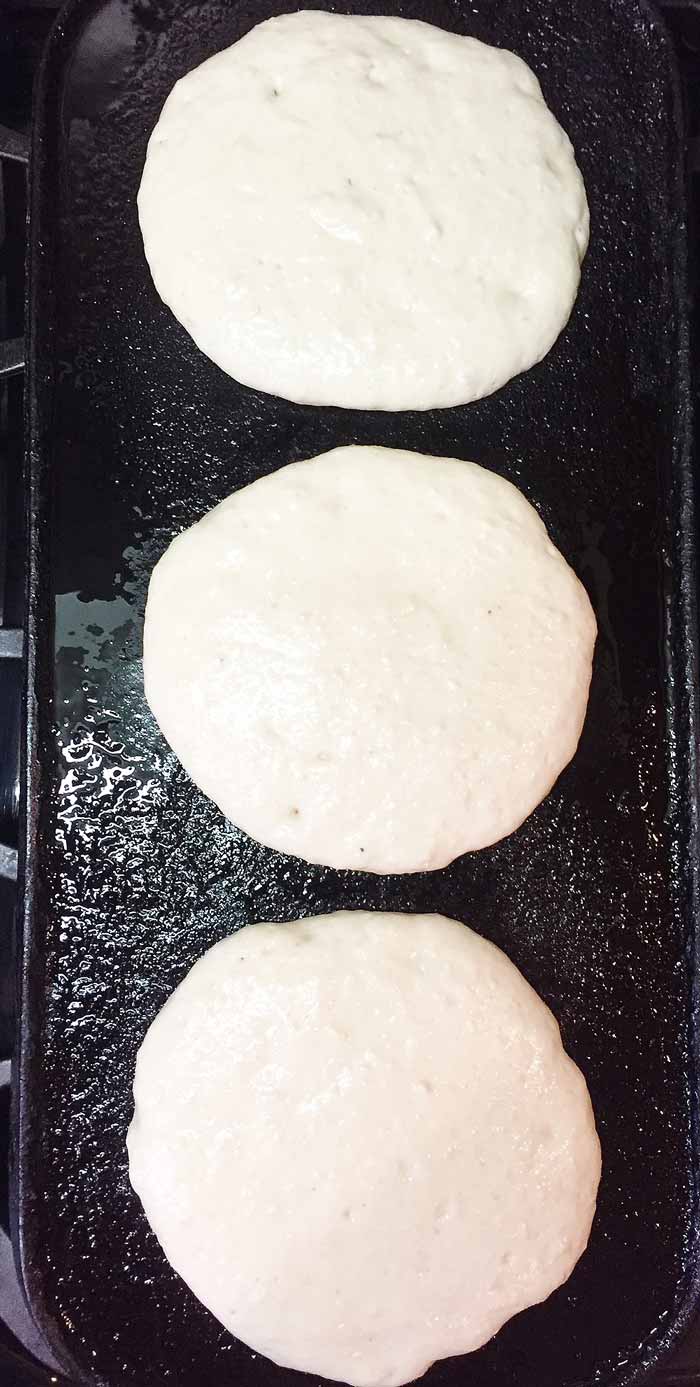 Old Fashioned Fluffy Vegan Pancake batter starting to bubble on the griddle.