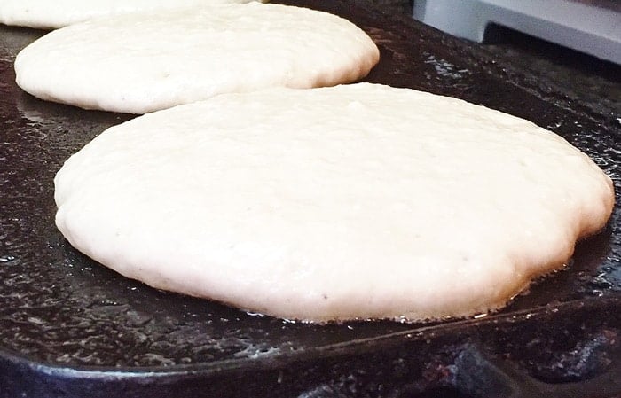 Old fashioned fluffy vegan pancake batter cooking on the griddle. 