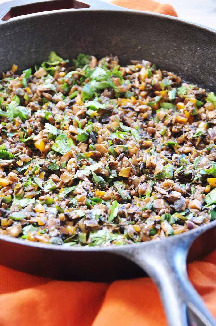 Smoky Mushroom Tinga (Vegan and Gluten-Free) in a cast-iron skillet with an orange towel underneath the pan