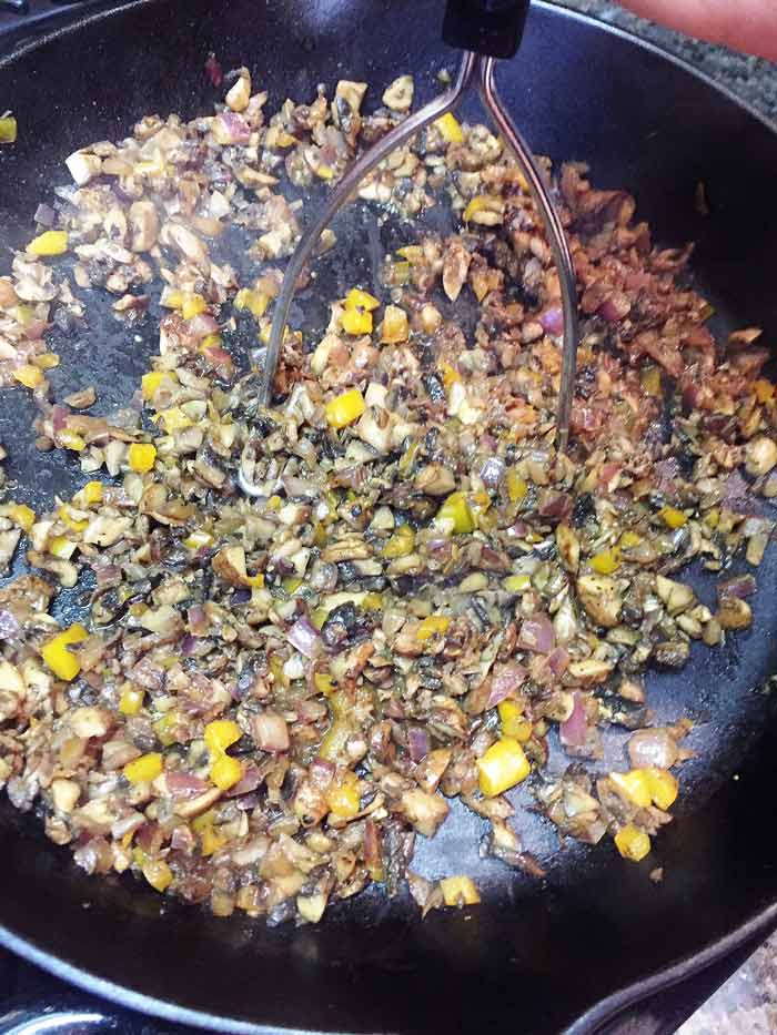 Mushroom tinga being mashed in a cast-iron skilet