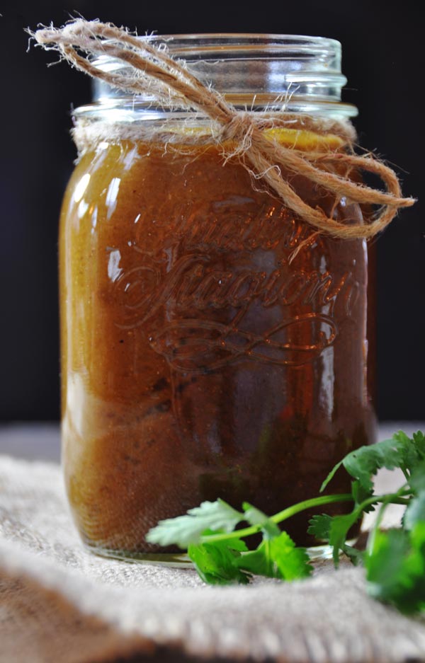 Homemade enchilada sauce in a mason jar with twine and a sprig of cilantro