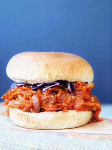 Pulled BBQ-Carrots with Homemade BBQ Sauce Sandwich on a wood board with shredded red cabbage