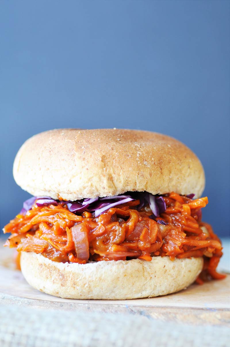A pulled carrot BBQ sandwich with shredded purple cabbage on a bun. 