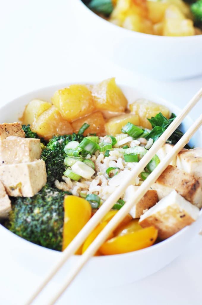 A white bowl with rice, broccoli, tofu, and pineapple.