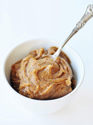 Date caramel in a white bowl with a silver spoon stuck in the center