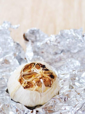 A head of roasted garlic on a piece of foil.