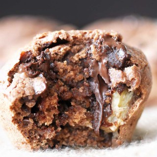 A chocolate banana muffin with a bite take out of it.