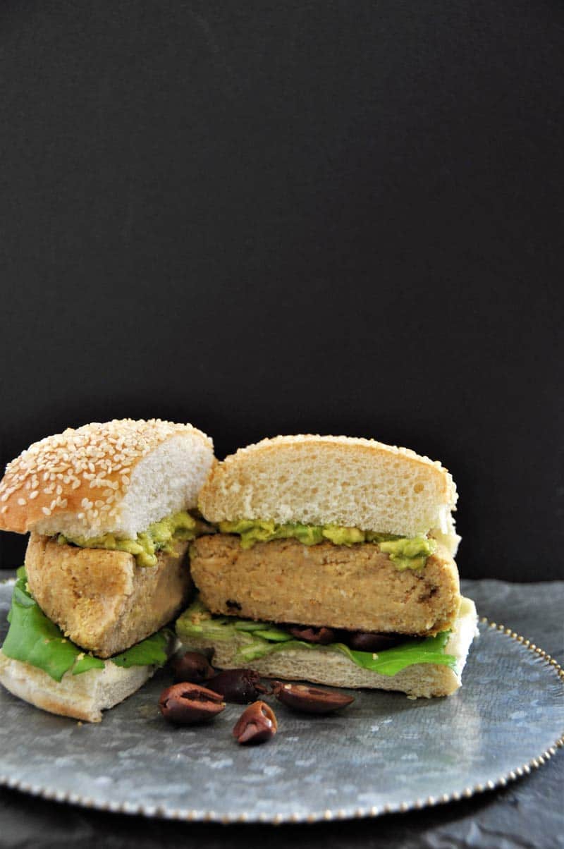 A hummus burger cut in half on a silver plate