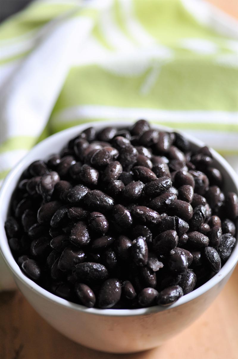 A white bowl filled with cooked black beans. 