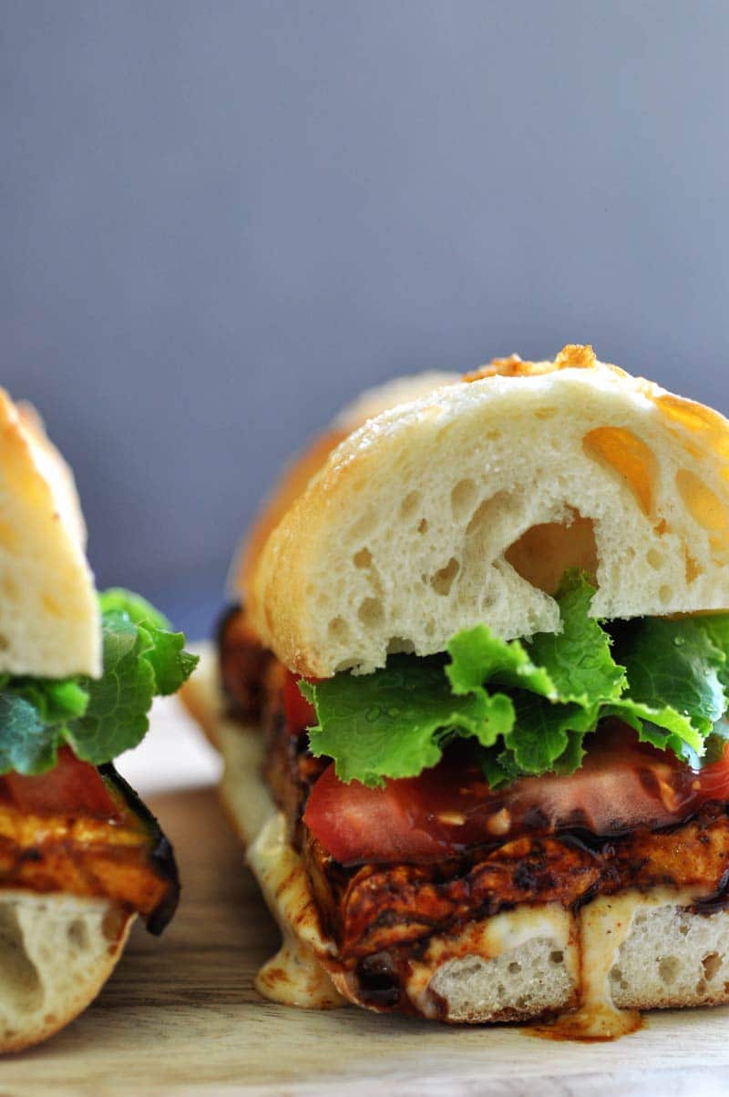 An ELT (eggplant, lettuce, and tomato) Sandwich with ranch dressing dripping down the side of the bread. 