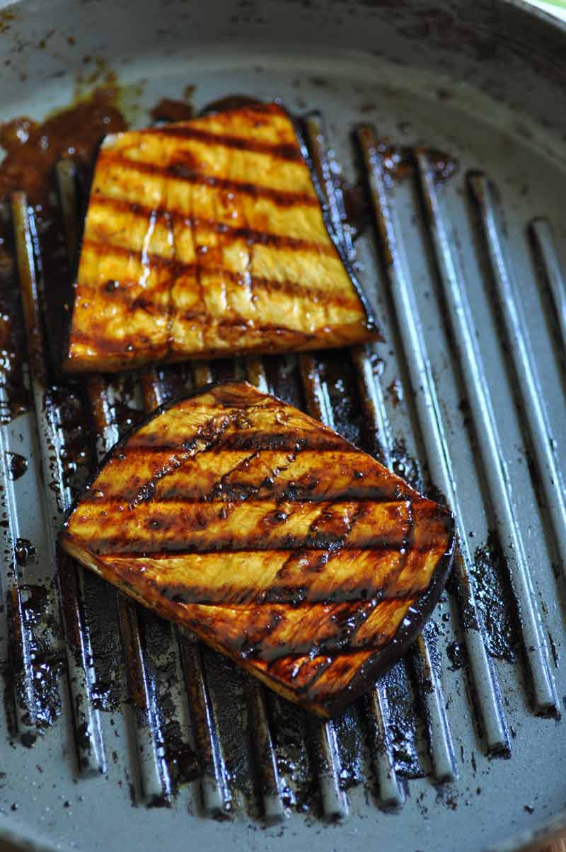 2 slices of marinated grilled eggplant on a grill pan.
