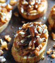 Apple Cinnamon Bruschetta on a baking sheet with chopped pecans scattered around the pan