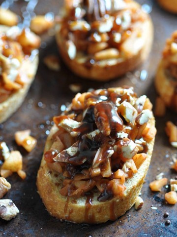 Apple Cinnamon Bruschetta on a baking sheet with chopped pecans scattered around the pan