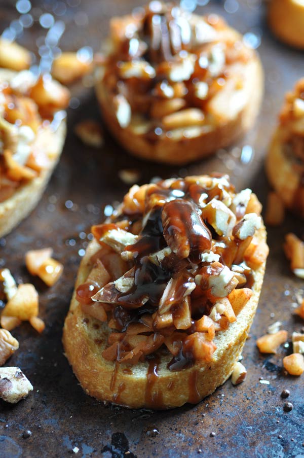 Apple Cinnamon Bruschetta on a baking sheet with chopped pecans scattered around the pan