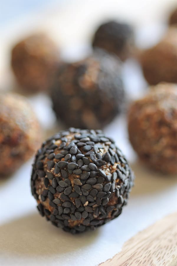 Healthy raw energy bites scattered on a piece of parchment paper on a wood board