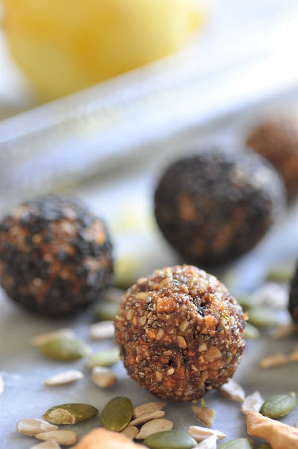 Energy bites on a baking sheet with pepitas and sunflower seeds. 