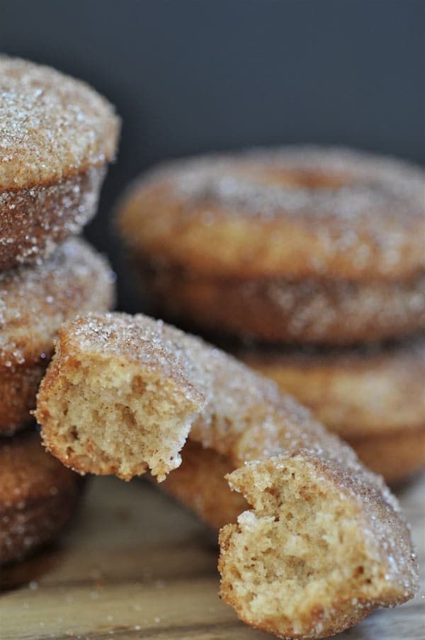 Baked apple cider doughnuts stacked and a half eaten one leaning on a stack of three doughnuts