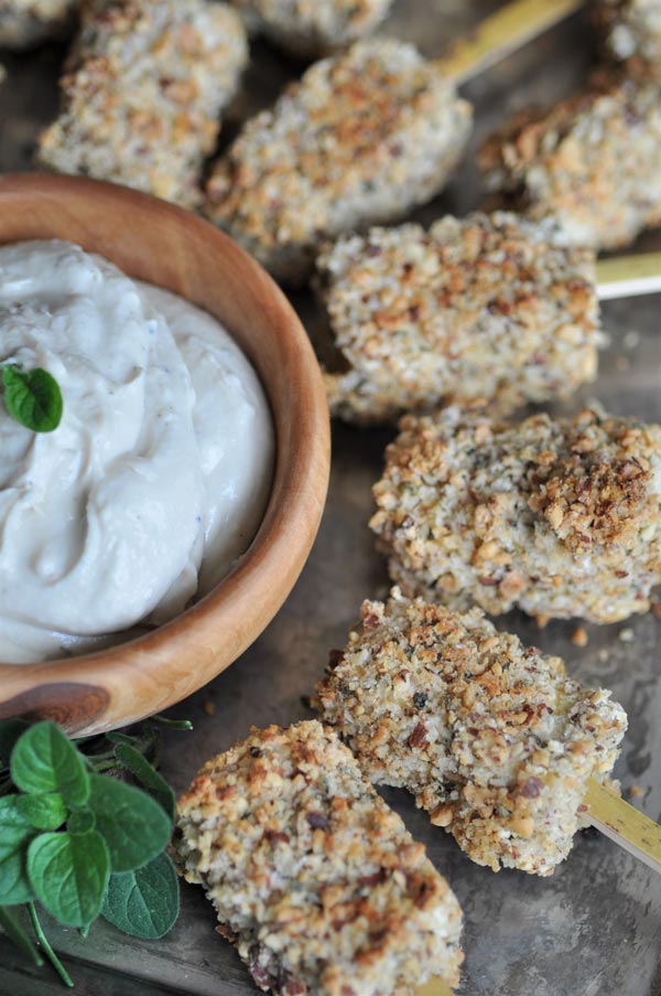 Almond crusted tofu bites on a silver tray with a wooden bowl of lemon ginger dip