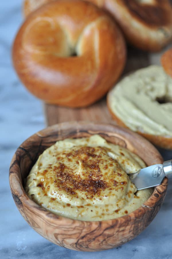 Vegan pumpkin spread sprinkled with coconut sugar in a wooden bowl with bagels on a wood board. 