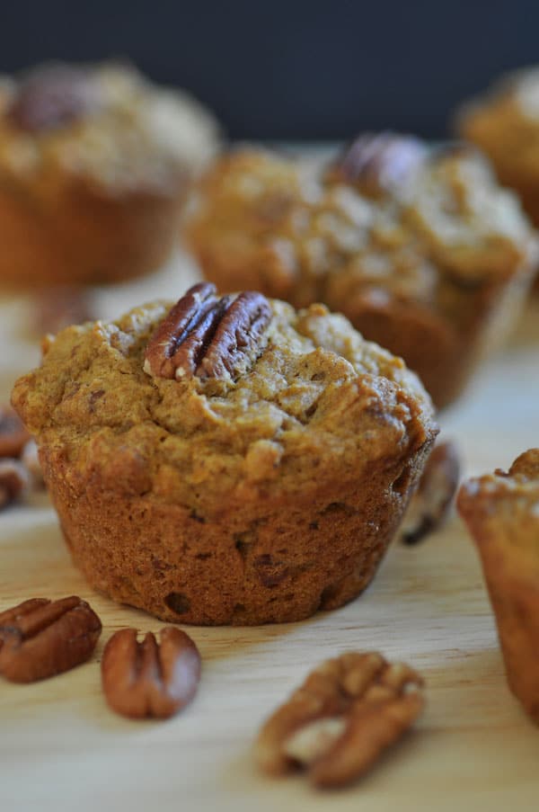 Individual vegan pumpkin pecan muffins with whole pecans.