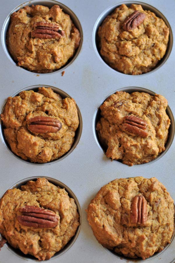 Perfectly golden brown baked vegan pumpkin pecan muffins in a muffin pan.