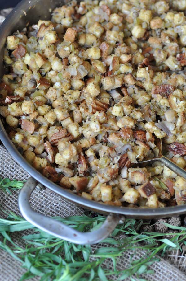 Vegan stuffing in a copper pan with fresh herbs next to the pan