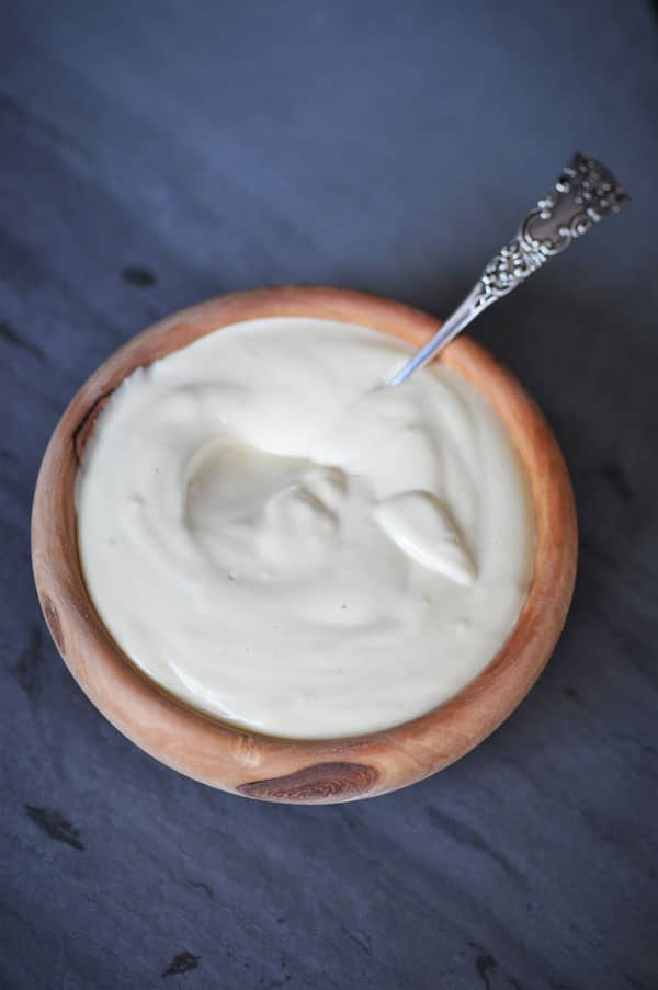 The ultimate vegan cheese sauce in a wood bowl with a silver spoon in the sauce.