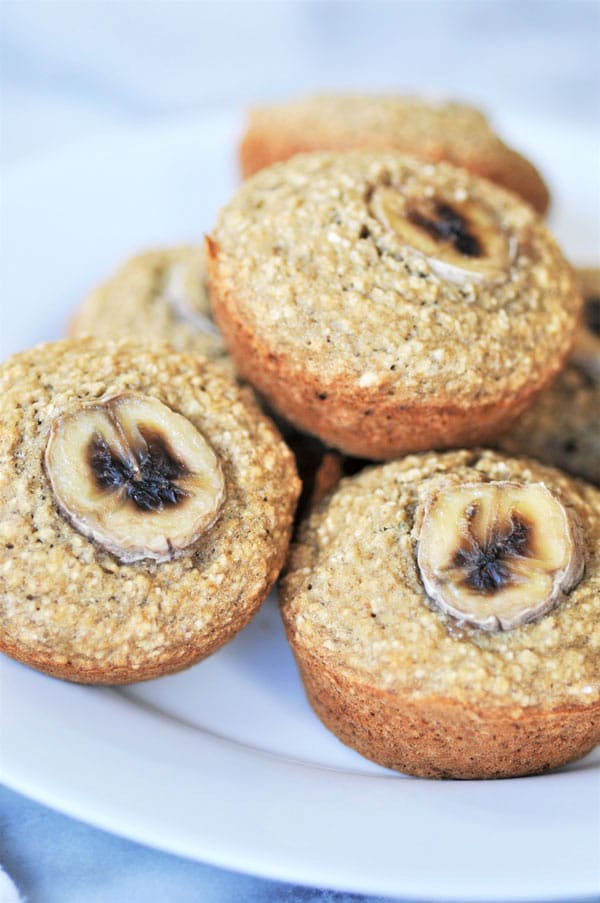 A close up shot of a pile of vegan and gluten-free banana muffins on a white plate