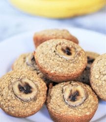 A stack of banana muffins on a white plate with bananas in the background