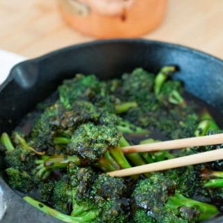 Homemade teriyaki broccoli in an iron skillet with a pair of chopsticks