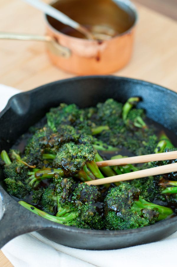 Homemade teriyaki broccoli in an iron skillet with a pair of chopsticks