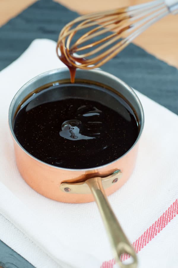 Homemade vegan teriyaki sauce in a copper pan with a silver whisk