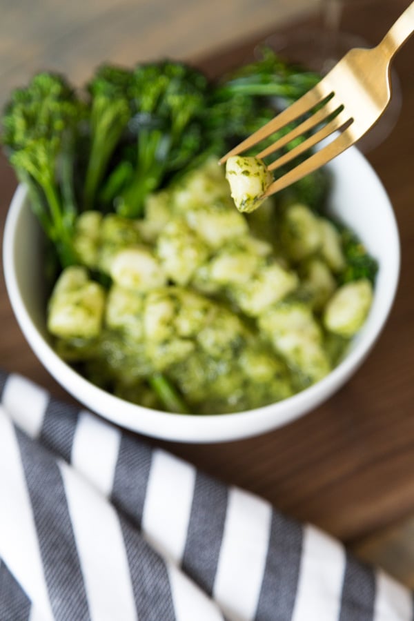 Close up of gnocchi with the bowl of gnocchi in the background with striped napkin