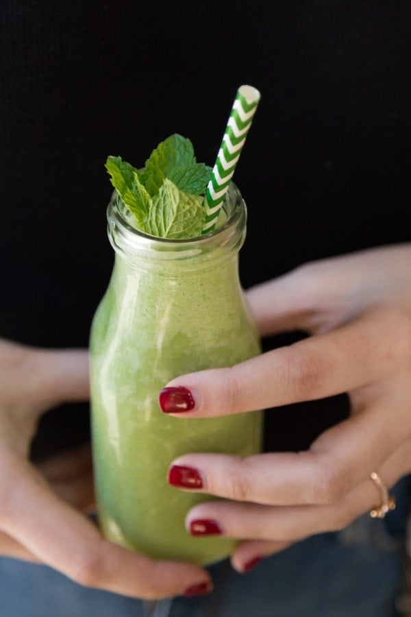 Shamrock Shake in a glass jar with a green and white straw being held