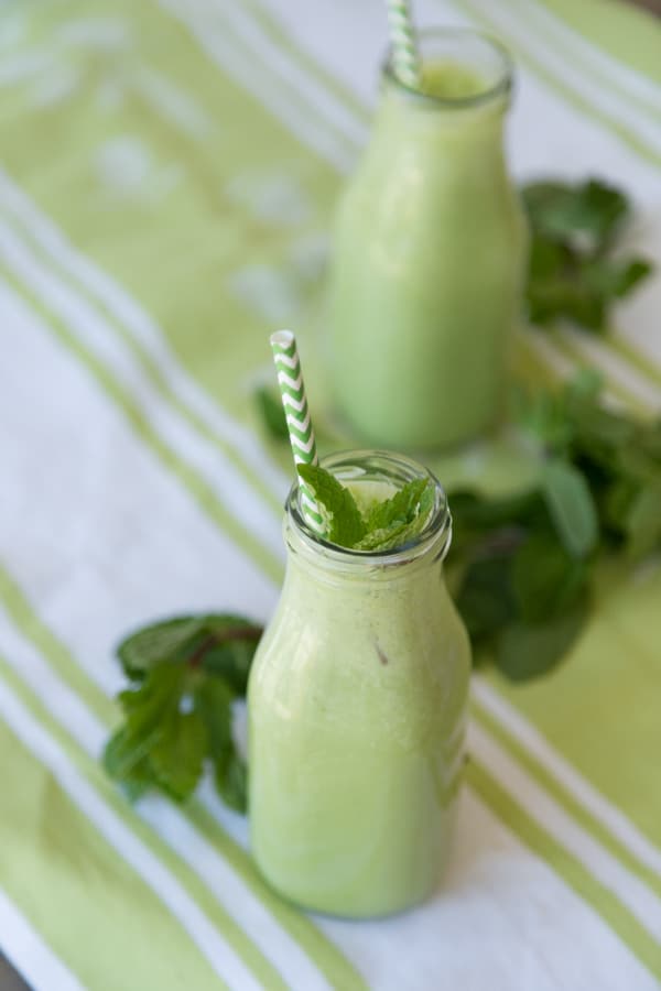 Shamrock shakes on a green and white towel with mint in glass containers