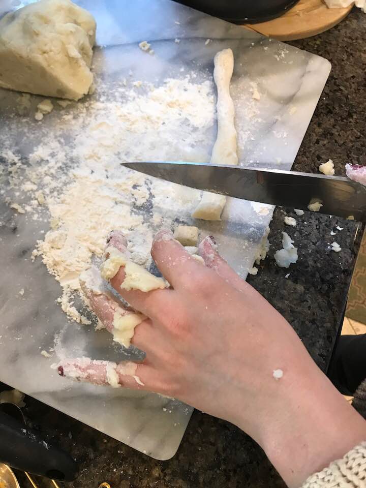 Slicing pieces of rolled out dough to make gnocchi