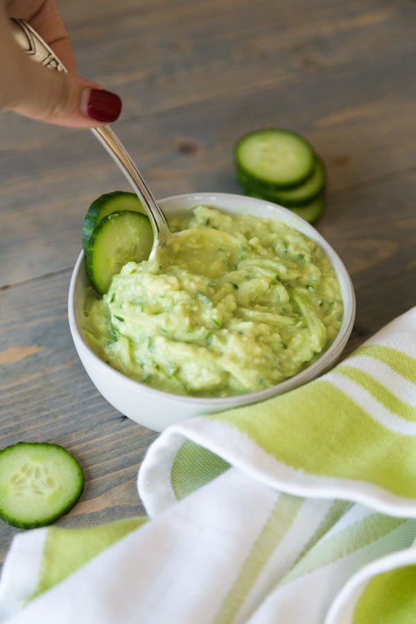 hand picking up spoon in tzatziki sauce