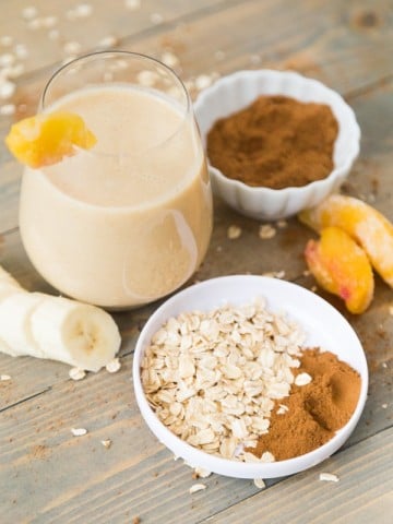 Peach cobbler smoothie with all ingredients in the background and foreground.