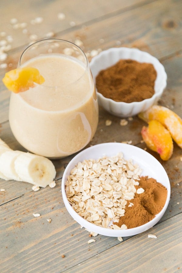 Peach cobbler smoothie with all ingredients in the background and foreground.